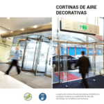 Cortinas de aire decorativas instaladas en la entrada de un edificio comercial con puertas giratorias y acristaladas, diseñadas para mantener el confort térmico sin renunciar al diseño.